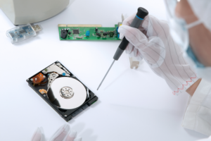 A technician with gloves on trying to retrieve lost data from an inaccessible hard drive