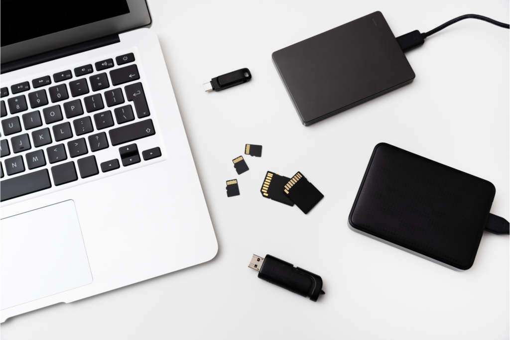A laptop with different kinds of portable digital storage devices beside it