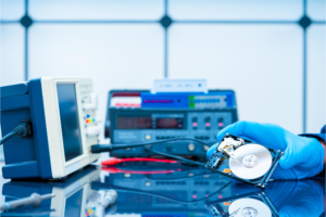 A technician with a rubber glove recovering data from a bad hard drive inside a data recovery lab